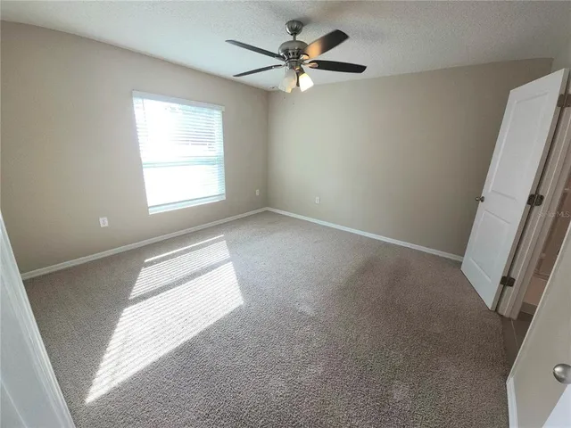 an empty room with windows and fan