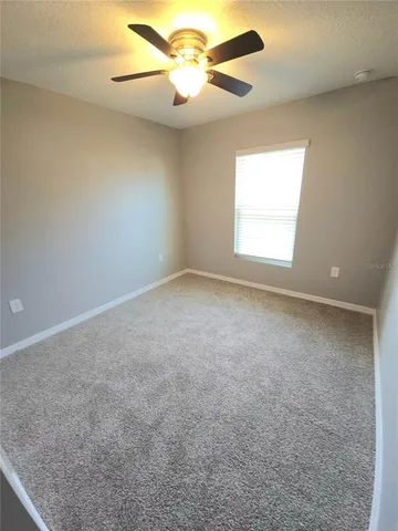 an empty room with a window and a fan