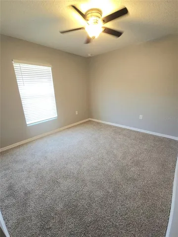 an empty room with windows and fan