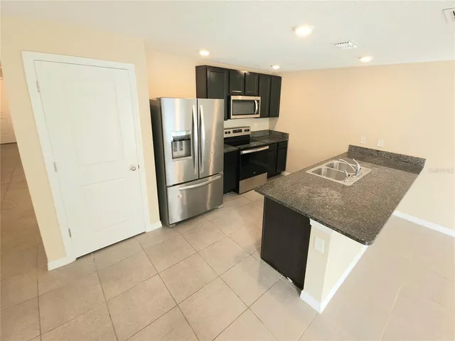 a kitchen with stainless steel appliances granite countertop a refrigerator a stove a sink and a microwave