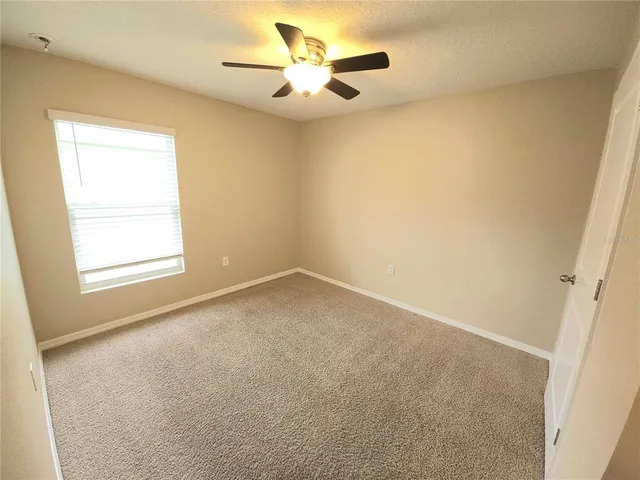 an empty room with a window and a ceiling fan