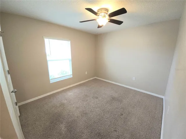 an empty room with a window and a fan