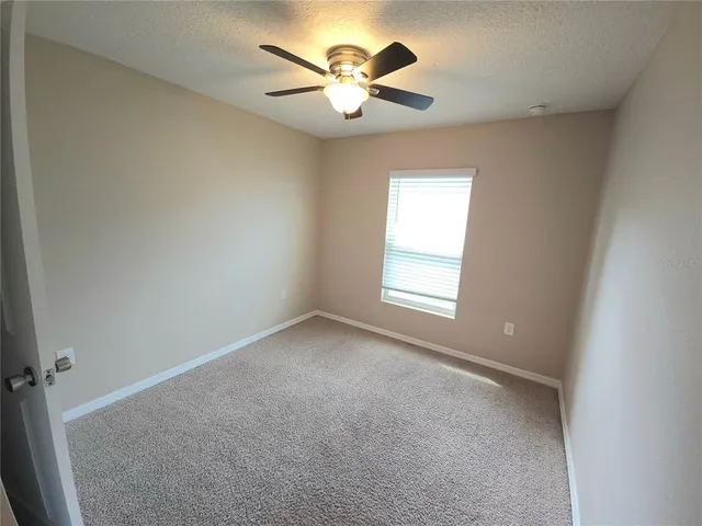 an empty room with a window and a ceiling fan