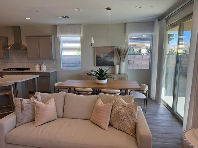 a kitchen with stainless steel appliances granite countertop a refrigerator a sink dishwasher a stove and a dining table with wooden floor