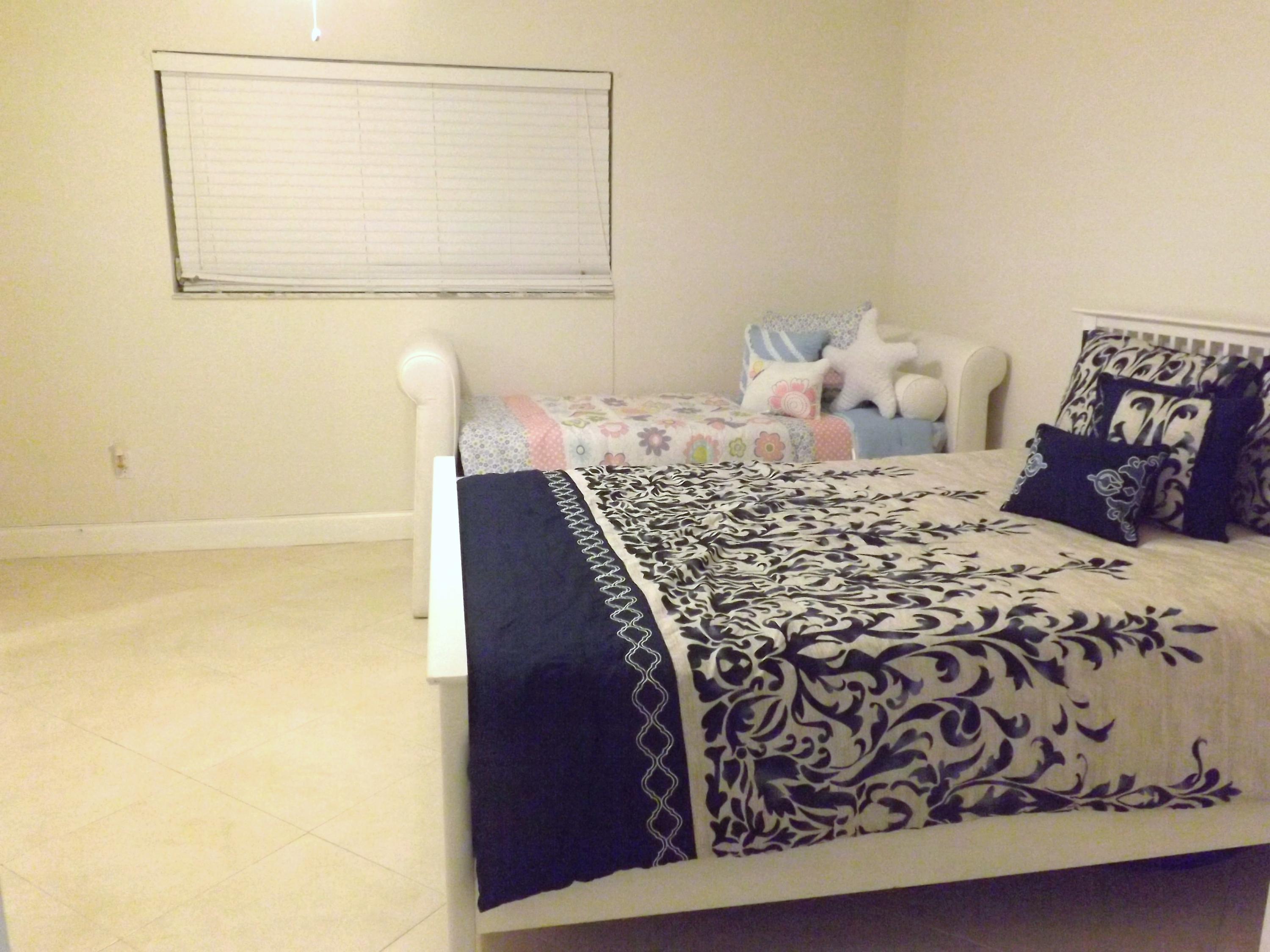 64 Davis Road Palm Springs, FL 33461 - Photo 19 of 32 a bed sitting in a bedroom next to a small yard