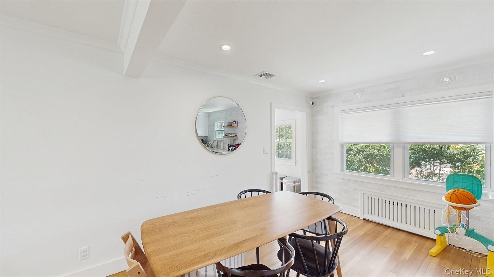 170 Wetherill Road Garden City, NY 11530 - Photo 6 of 23 Dining room with crown molding, visible vents, radiator heating unit, and light wood finished floors
