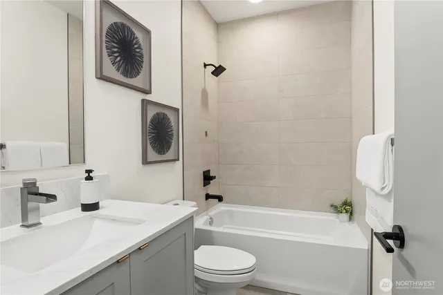 a bathroom with a granite countertop bathtub sink vanity mirror and toilet