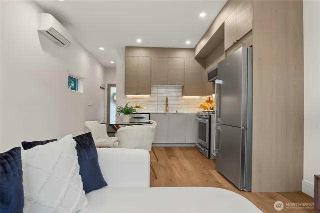 a living room with stainless steel appliances furniture a refrigerator and kitchen view