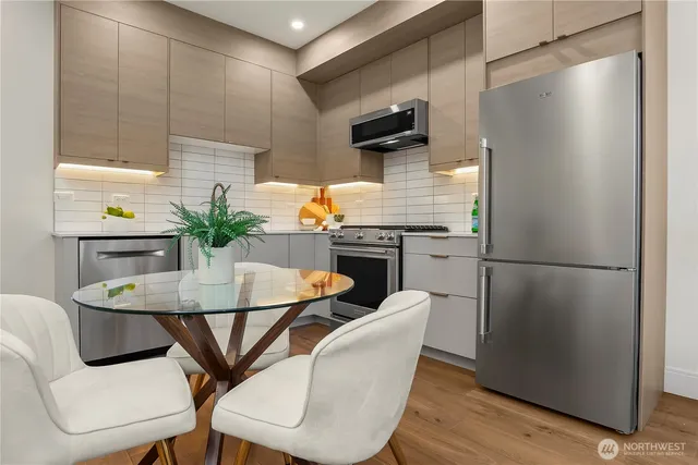 a kitchen with stainless steel appliances granite countertop a dining table chairs and a refrigerator