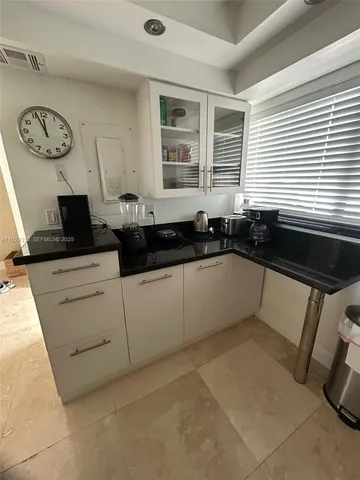 a spacious bedroom with a bed and a lamp on the dresser