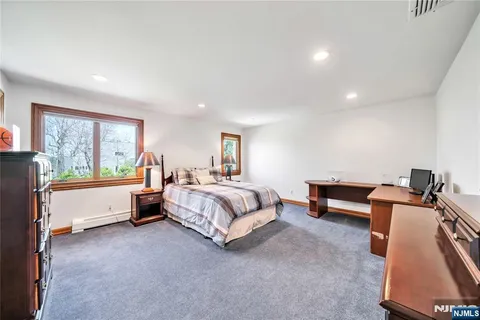 a spacious bedroom with a bed a dresser and a bookshelf