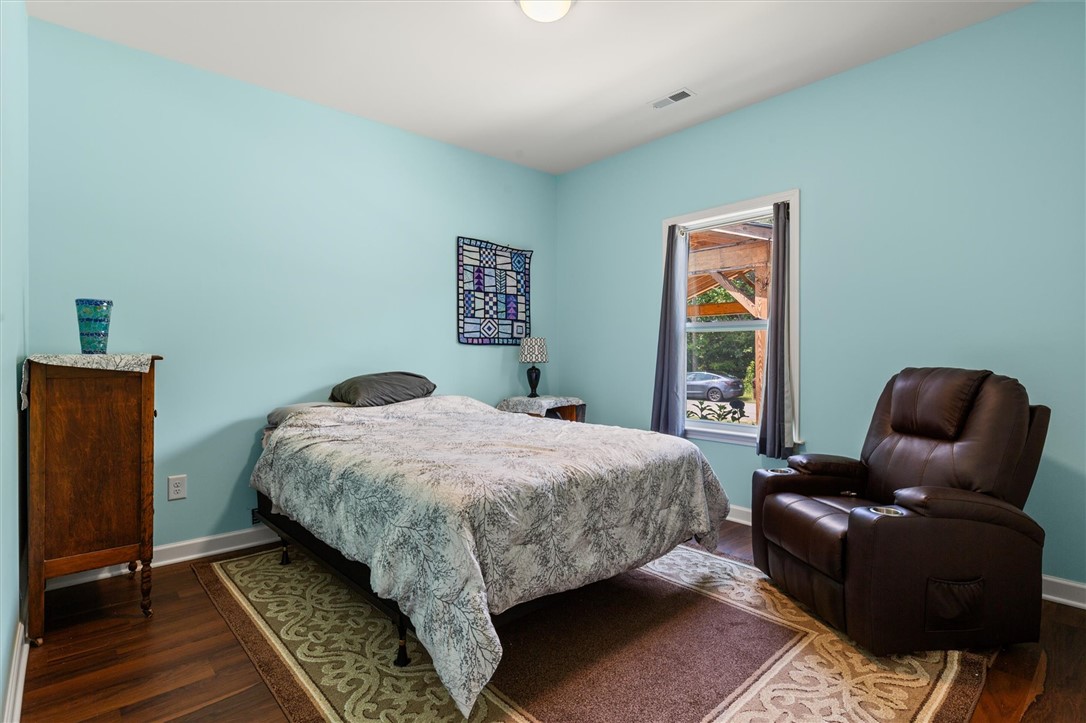 67 Sawblade Ridge Marietta, SC 29661 - Photo 21 of 37 Rich hardwood flooring anchors this cozy bedroom featuring a classic window that welcomes natural light.