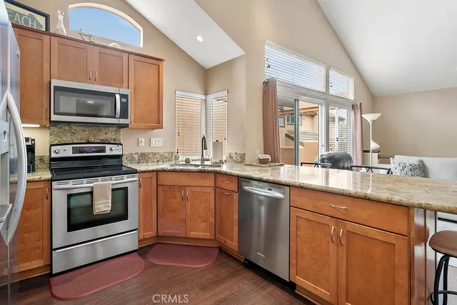 a kitchen with granite countertop a sink stainless steel appliances and cabinets