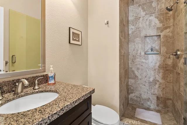 a bathroom with a granite countertop sink toilet a mirror and shower