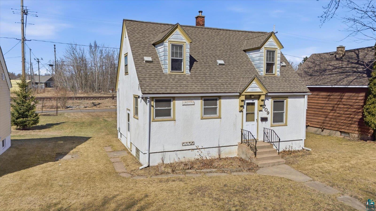 709 Michigan Street Hibbing, MN 55746 - Photo 28 of 47 Cape cod house with a front yard, a chimney, a shingled roof, and entry steps
