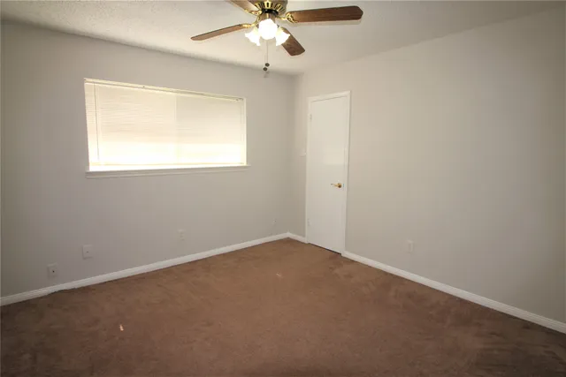 an empty room with a window and a fan