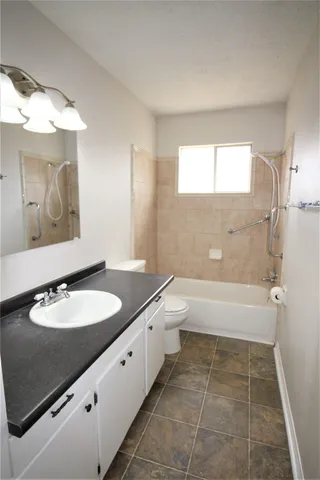 a bathroom with a granite countertop sink a toilet a mirror and bathtub