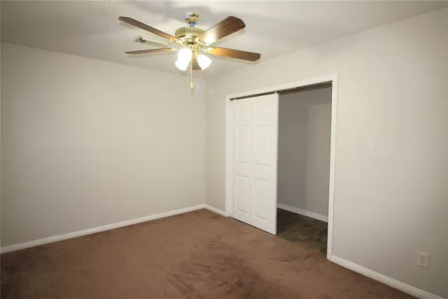 an empty room with a chandelier fan and a ceiling fan