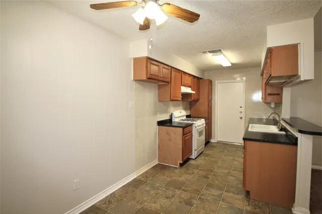 a kitchen with granite countertop a sink a stove top oven and cabinets