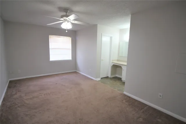 an empty room with a chandelier fan and windows