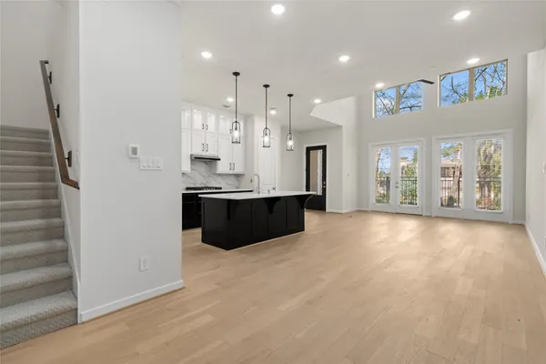 a large white kitchen with a large counter top a sink stainless steel appliances and cabinets