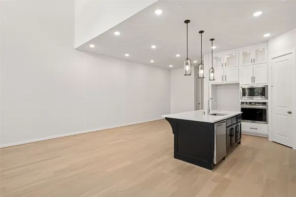 a view of an empty room with kitchen and window