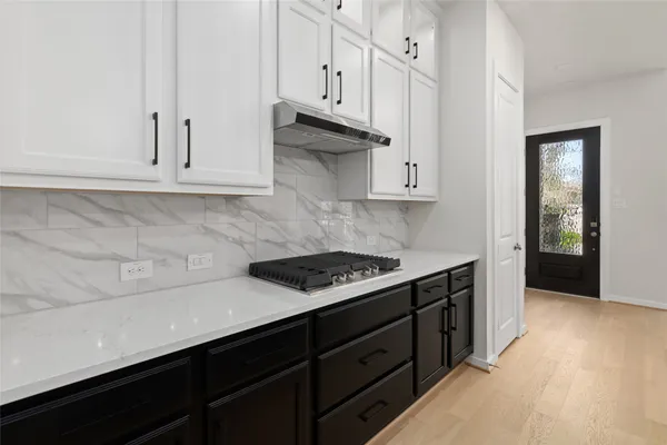 a kitchen with kitchen island a sink a stove a refrigerator and white cabinets