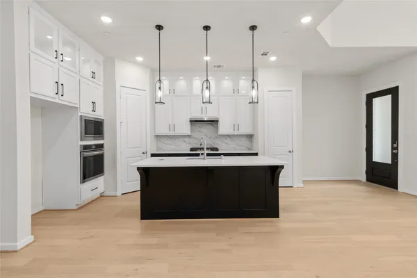 a large kitchen with stainless steel appliances granite countertop a refrigerator a oven a white and white cabinets