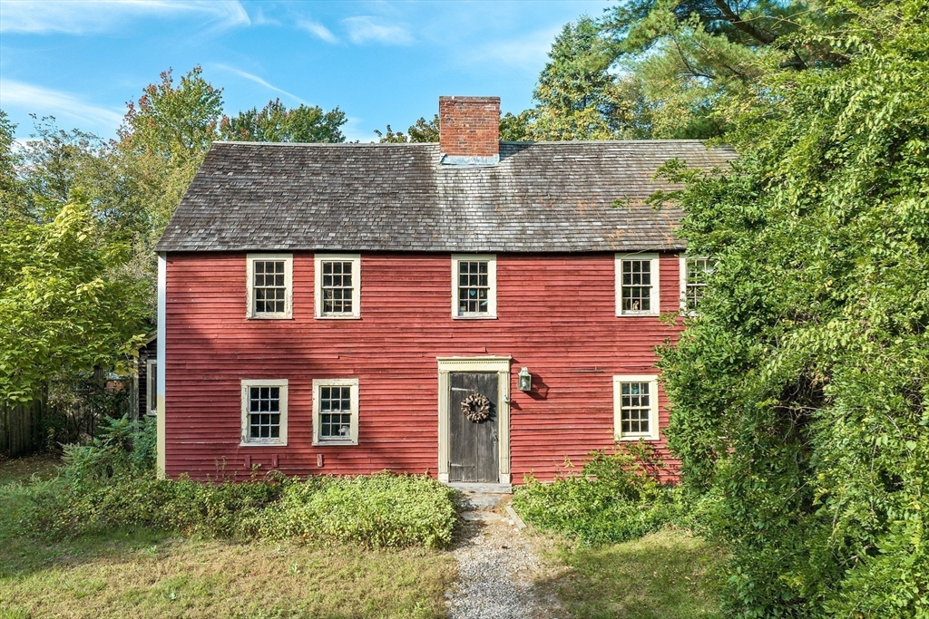 a front view of a house with plants and trees