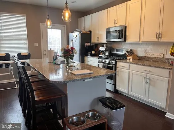 a kitchen with stainless steel appliances a stove a sink a microwave a stove and white cabinets