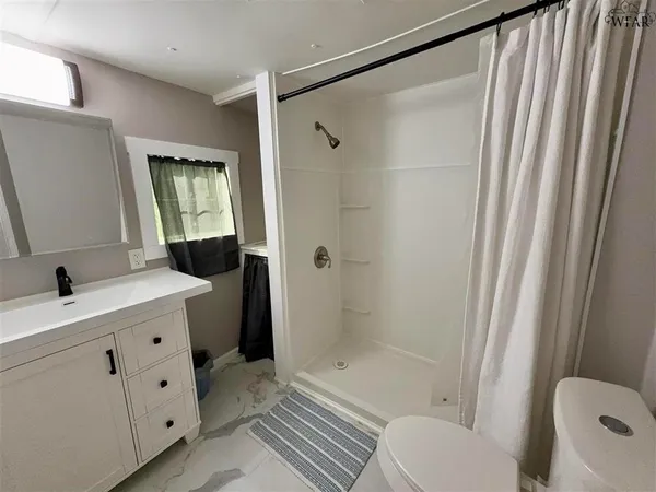 a bathroom with a granite countertop sink toilet and shower