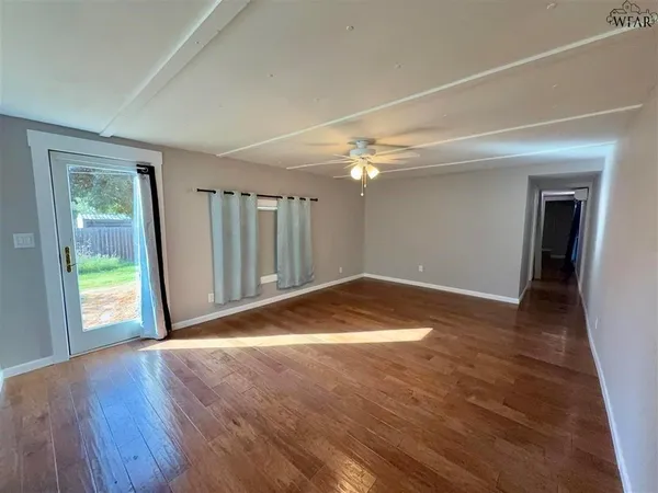 a view of empty room with wooden floor and fan