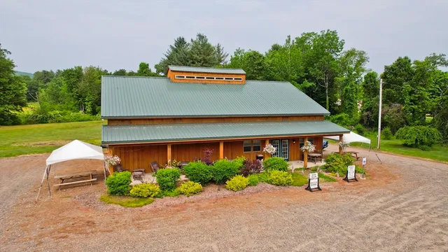 a sign that is sitting in front of a house with potted plants