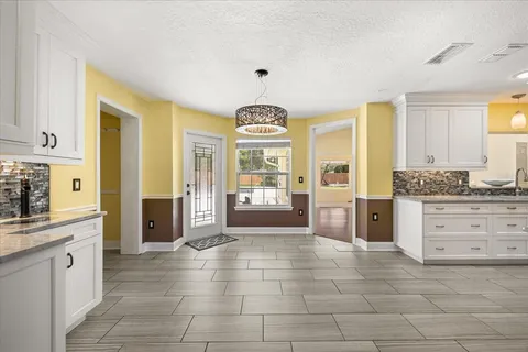 a large kitchen with granite countertop a stove a sink a refrigerator and a fireplace