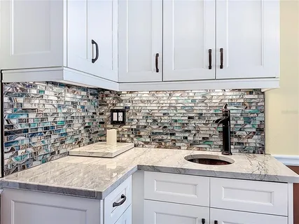 a sink with granite countertop white cabinets and white appliances