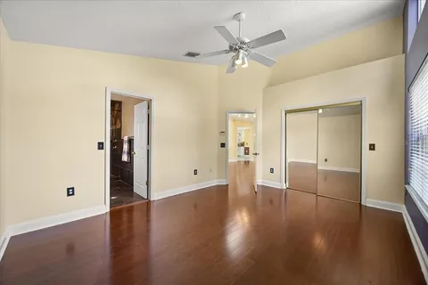 an empty room with wooden floor and a ceiling fan