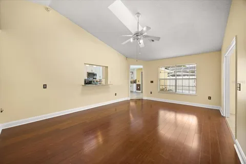 an empty room with wooden floor fan and windows