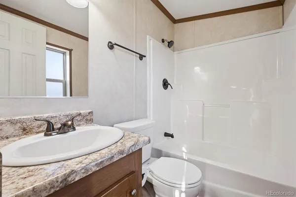 a bathroom with a granite countertop sink toilet a mirror and shower