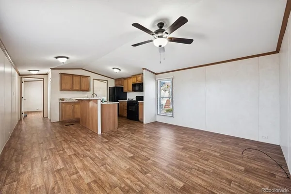 a view of a electric appliances in kitchen and empty room with wooden floor