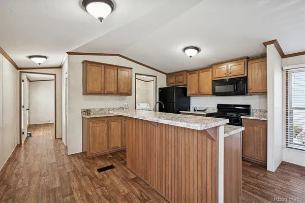 a kitchen with stainless steel appliances a stove top oven a sink dishwasher and a refrigerator with wooden floor