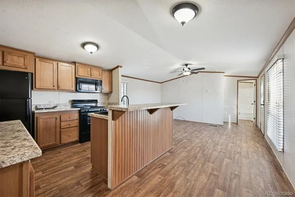 a kitchen with granite countertop a refrigerator oven a sink dishwasher and wooden cabinets with wooden floor