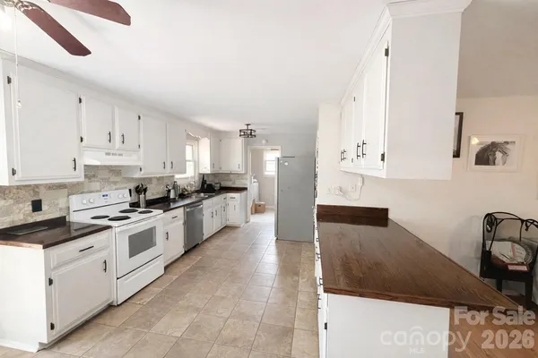 a large white kitchen with stainless steel appliances granite countertop a sink and cabinets