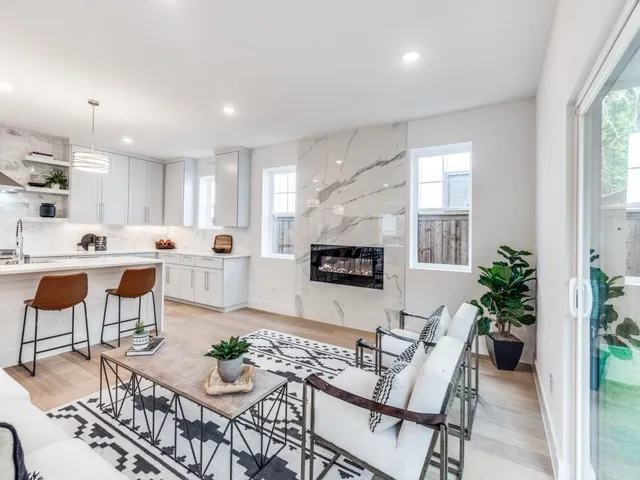 a living room with furniture kitchen view and a large window