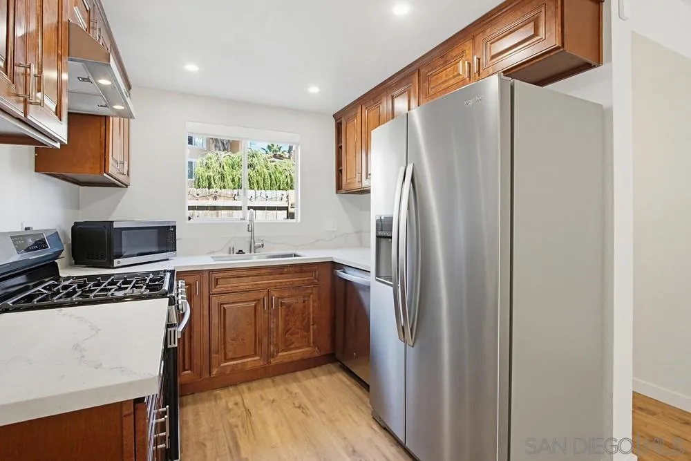 5130 North River Road, Unit B Oceanside, CA 92057 - Photo 18 of 51 a kitchen with stainless steel appliances granite countertop a refrigerator a sink dishwasher a stove and white cabinets with wooden floor