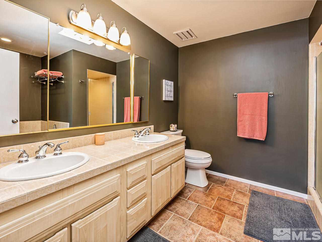 3447 Skyline Boulevard Reno, NV 89509 - Photo 16 of 24 a bathroom with a granite countertop sink a toilet and a mirror