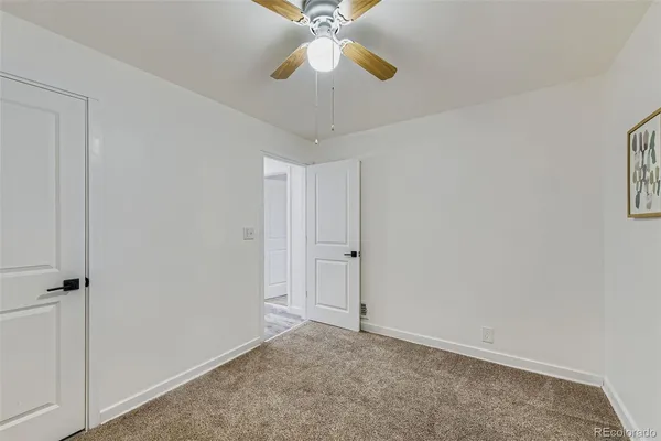 a view of an empty room and chandelier fan