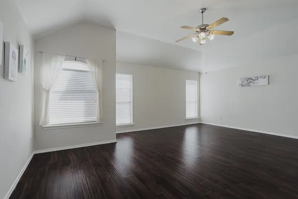 an empty room with wooden floor and windows