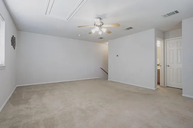 an empty room with a chandelier fan and windows