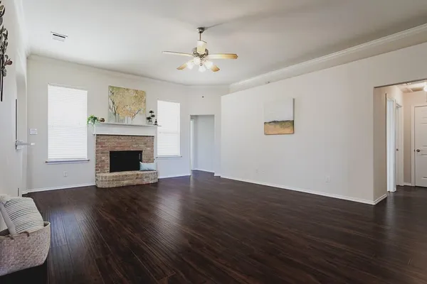 a view of an empty room with wooden floor and a fireplace