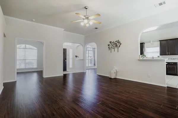 a view of an empty room with wooden floor and a ceiling fan